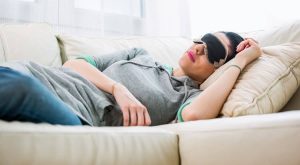 woman lying on couch with eye mask