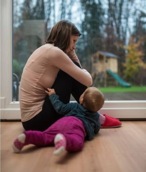 Depressed mom postpartum staring out window and ignoring baby
